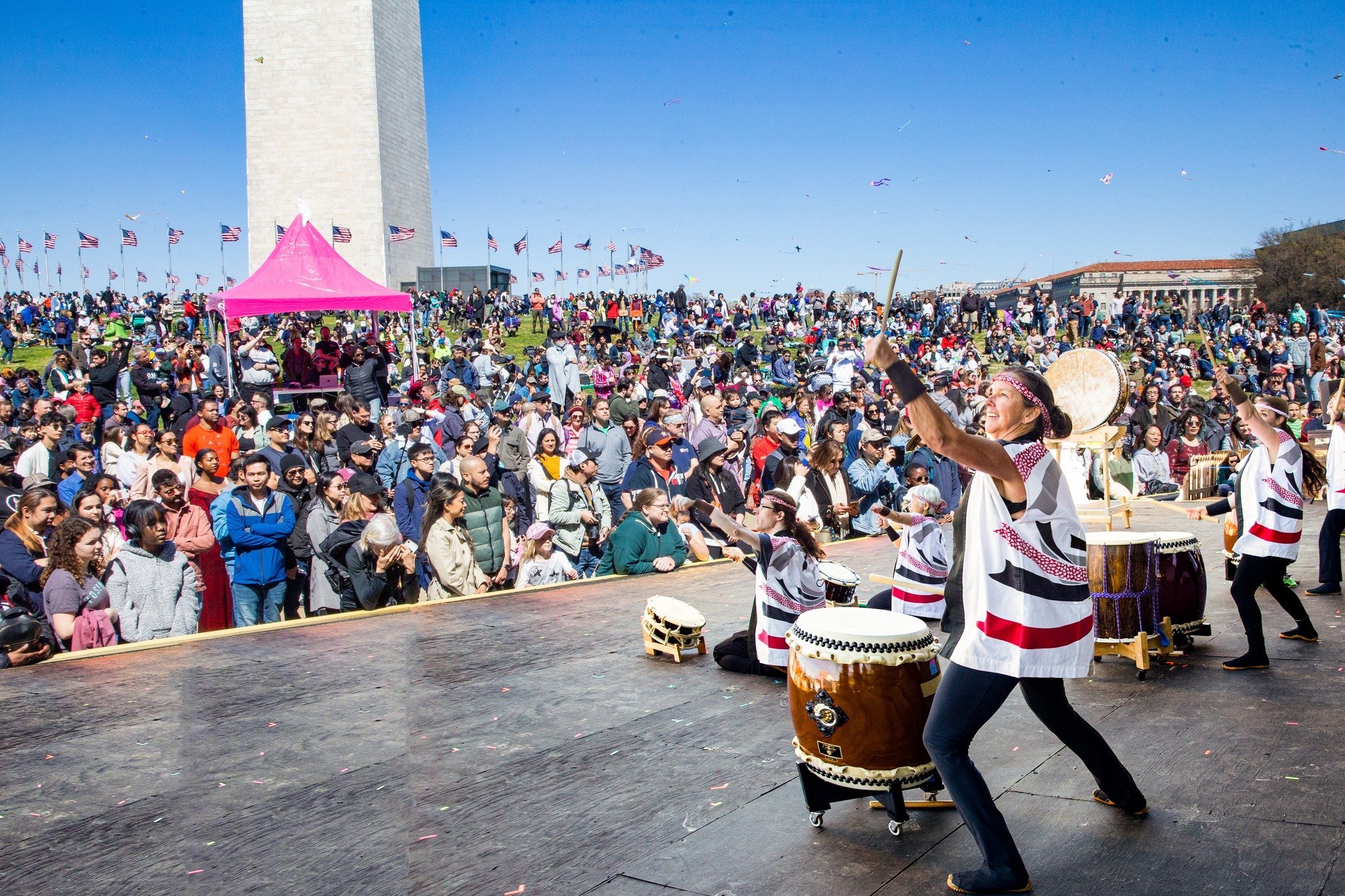 taiko players performing on stage with the Washington Monument in the background